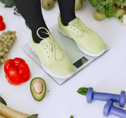 Person standing on scales surrounded by fresh produce and fitness equipment symbolizing a balanced lifestyle.